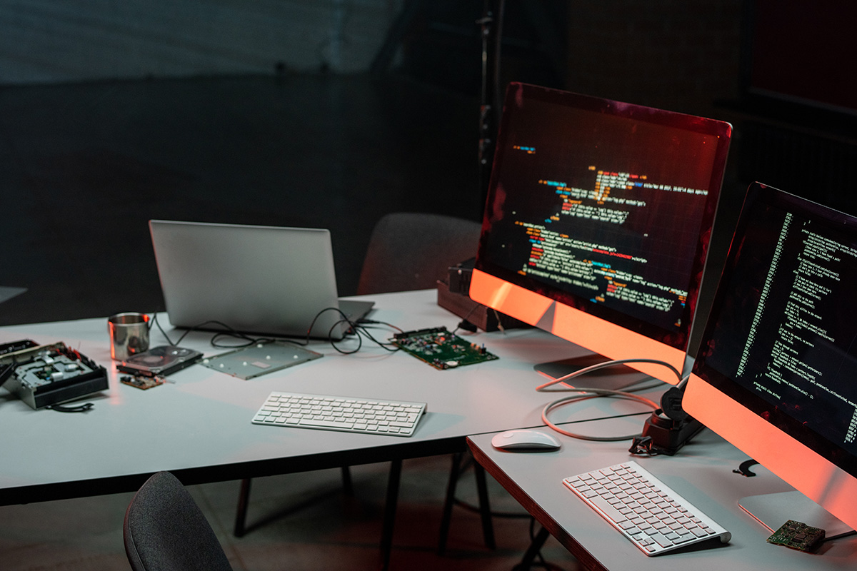 laptop and two computer monitors on desks